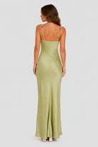 Woman wearing a green evening gown with thin straps on a white background