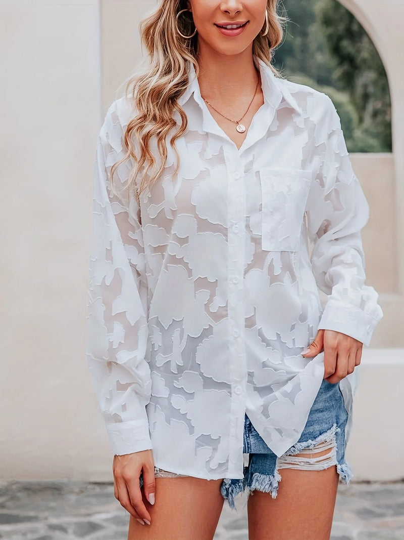Woman wearing a white lace cover-up over denim shorts outdoors.