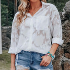 Person wearing a white camouflage shirt and denim shorts outdoors.