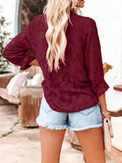 Woman wearing a burgundy floral-patterned blouse and denim shorts outdoors.