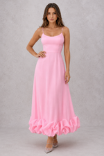 Woman wearing a pink dress with ruffled hem on a gray background