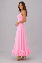 Woman wearing a pink dress with ruffled hem on a gray background