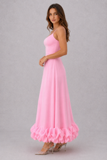 Woman wearing a pink dress with ruffled hem on a gray background