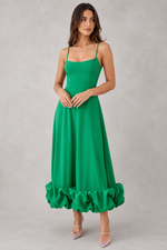 Woman wearing a green dress with ruffled hem on a gray background
