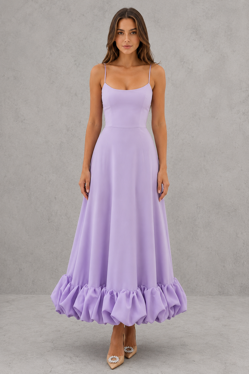 Woman wearing a purple dress with ruffled hem against a gray background