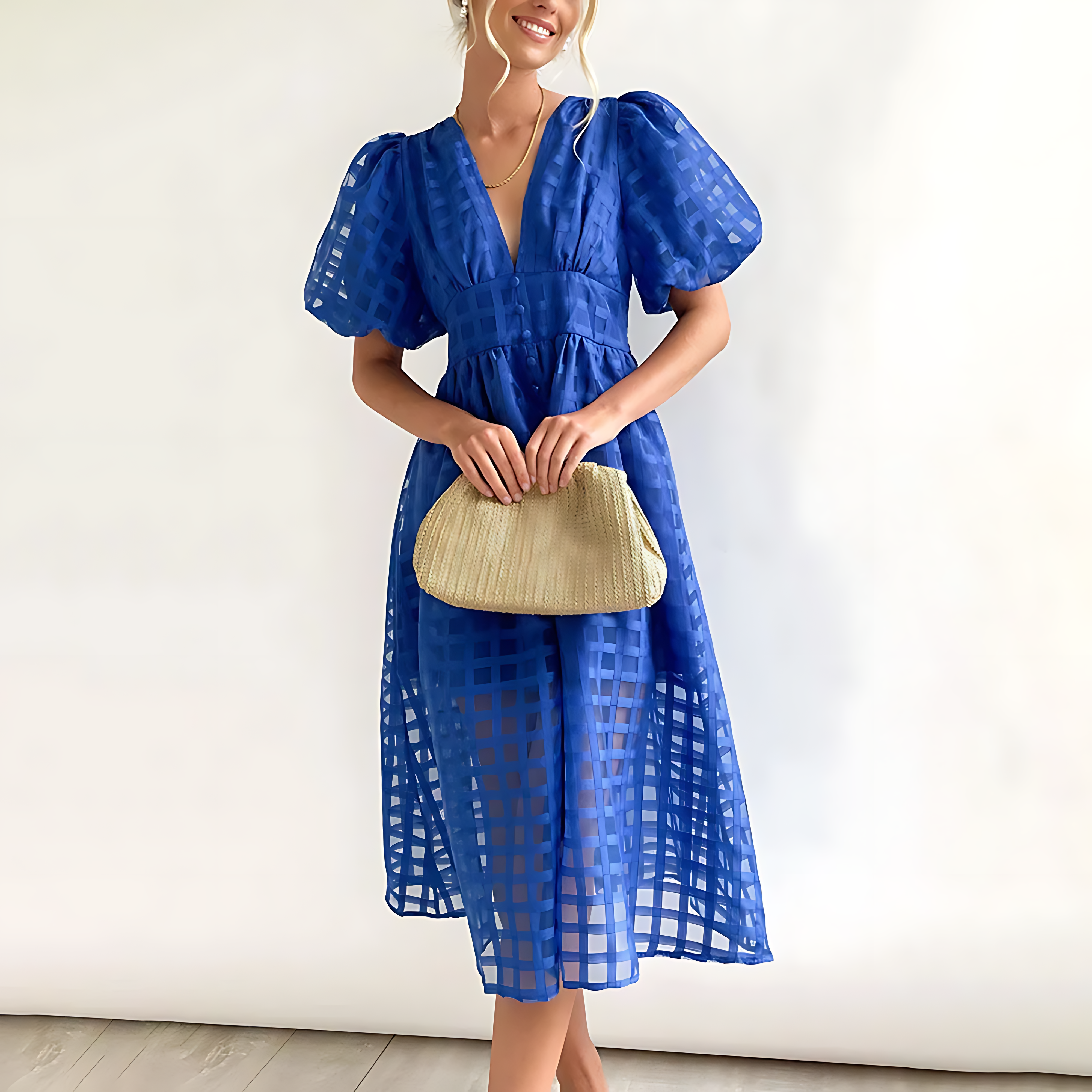 Woman wearing a blue dress holding a beige clutch against a white background