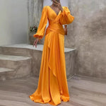 Woman wearing a long, flowing orange dress in an outdoor setting.
