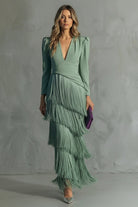 Woman wearing a green dress with a fringed skirt against a gray background
