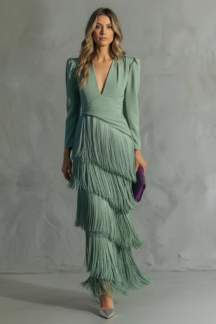 Woman wearing a green dress with a fringed skirt against a gray background