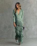 Woman wearing a green dress with fringes against a gray background