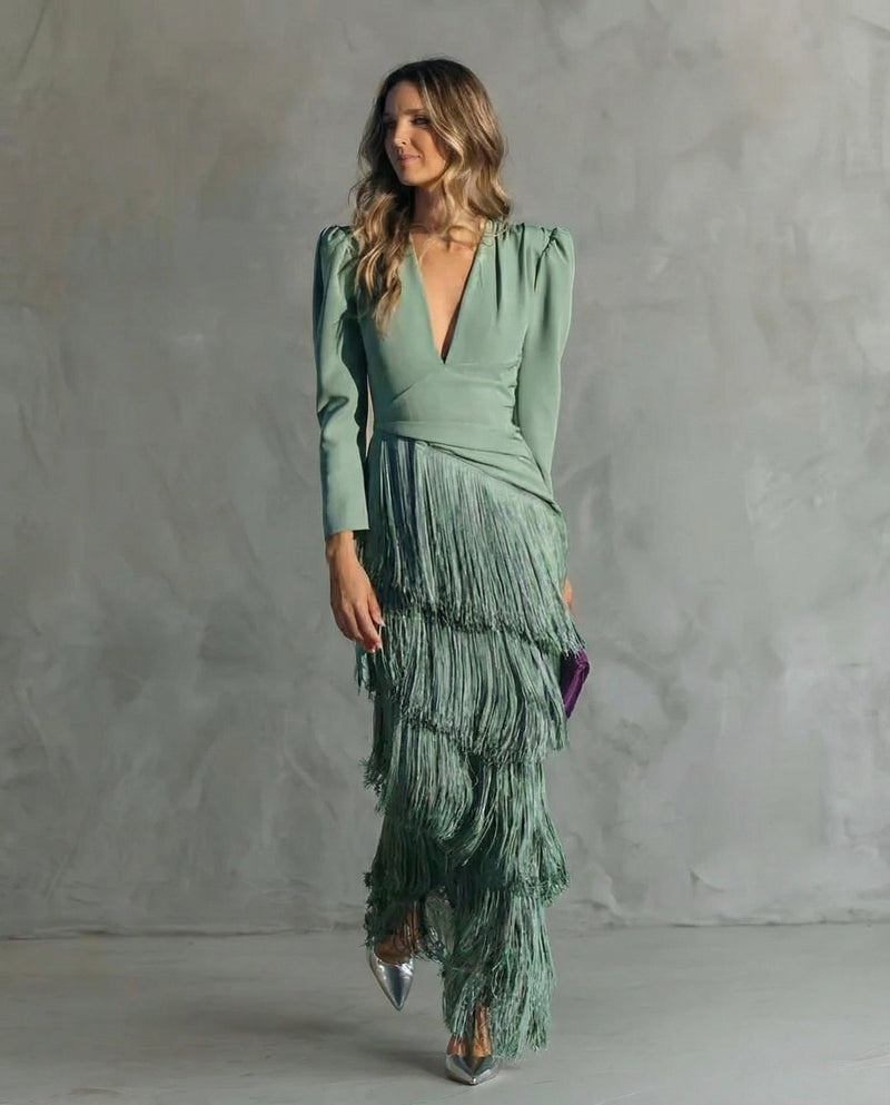 Woman wearing a green dress with fringes against a gray background