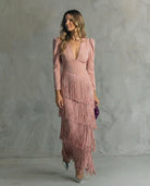Woman wearing a pink dress with fringe details against a gray background