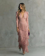 Woman wearing a pink dress with fringe details against a gray background