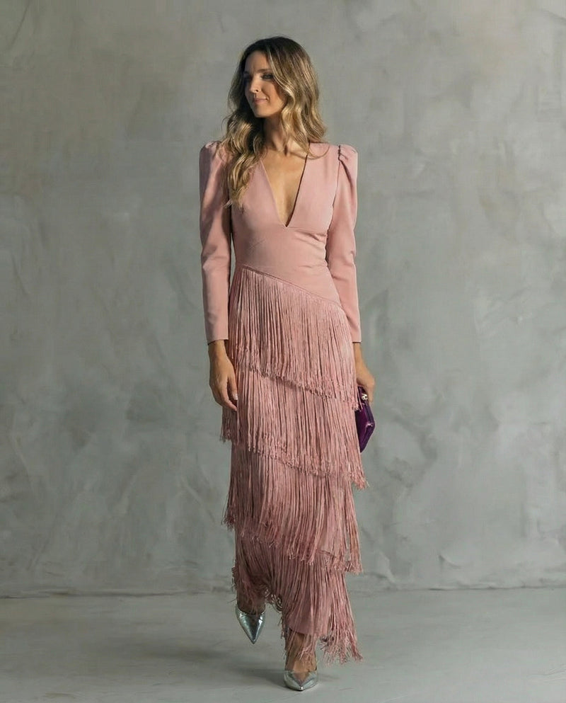 Woman wearing a pink dress with fringe details against a gray background