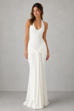 Woman wearing a white halter neck gown on a gray background
