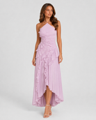 Woman wearing a lilac halter neck dress with ruffled layers on a white background
