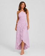 Woman wearing a lilac halter neck dress with ruffled layers on a white background