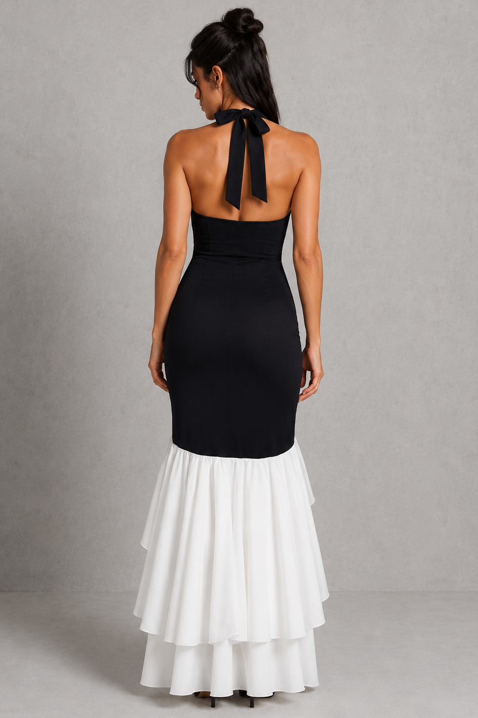 Woman wearing a black halter neck dress with a white skirt against a gray background