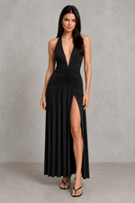 Woman wearing a black evening gown with a plunging neckline and high slit on a gray background