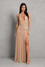 Woman wearing a beige evening gown with a high slit on a gray background