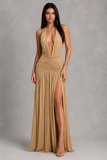 Woman wearing a beige halter neck gown with a high slit on a gray background