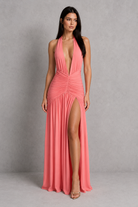 Woman wearing a pink halter neck dress with a slit on a gray background