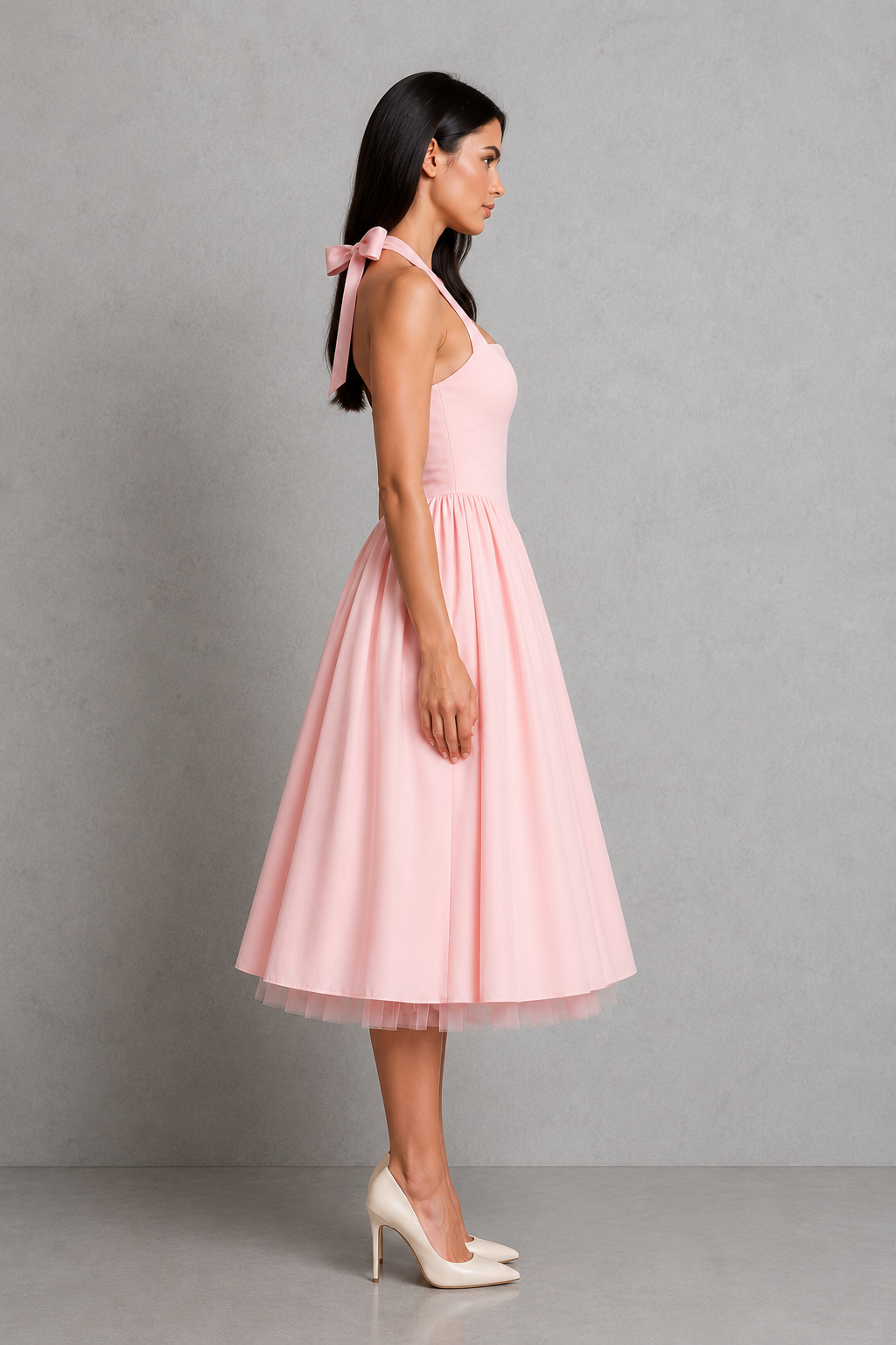 Woman wearing a pink dress with a bow detail on a gray background