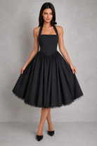 Woman wearing a white halter neck dress against a gray background