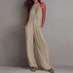 Woman wearing a beige halter neck jumpsuit against a plain background