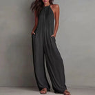 Woman wearing a dark gray jumpsuit against a plain background