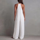 Woman wearing a white halter neck jumpsuit against a gray background