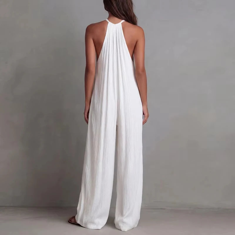 Woman wearing a white halter neck jumpsuit against a gray background