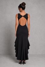 Woman wearing a black dress with an open back against a gray background