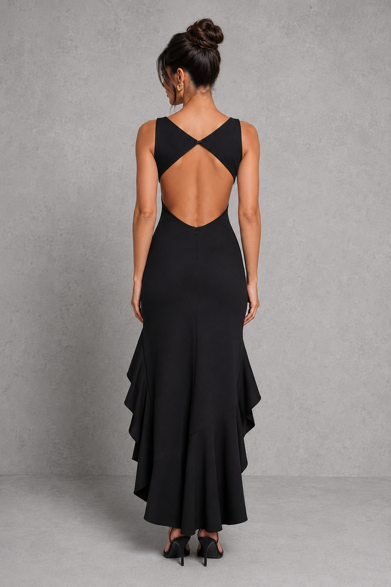 Woman wearing a black dress with an open back against a gray background