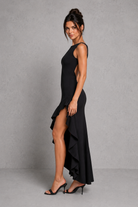 Woman wearing a black dress with a high slit on a gray background