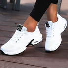 White athletic shoes with black accents on a wooden floor