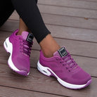 Purple sneakers with white soles worn on a wooden floor