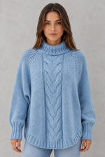 Woman wearing a blue knitted sweater against a gray background