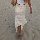 Person wearing a white lace skirt on a sandy beach