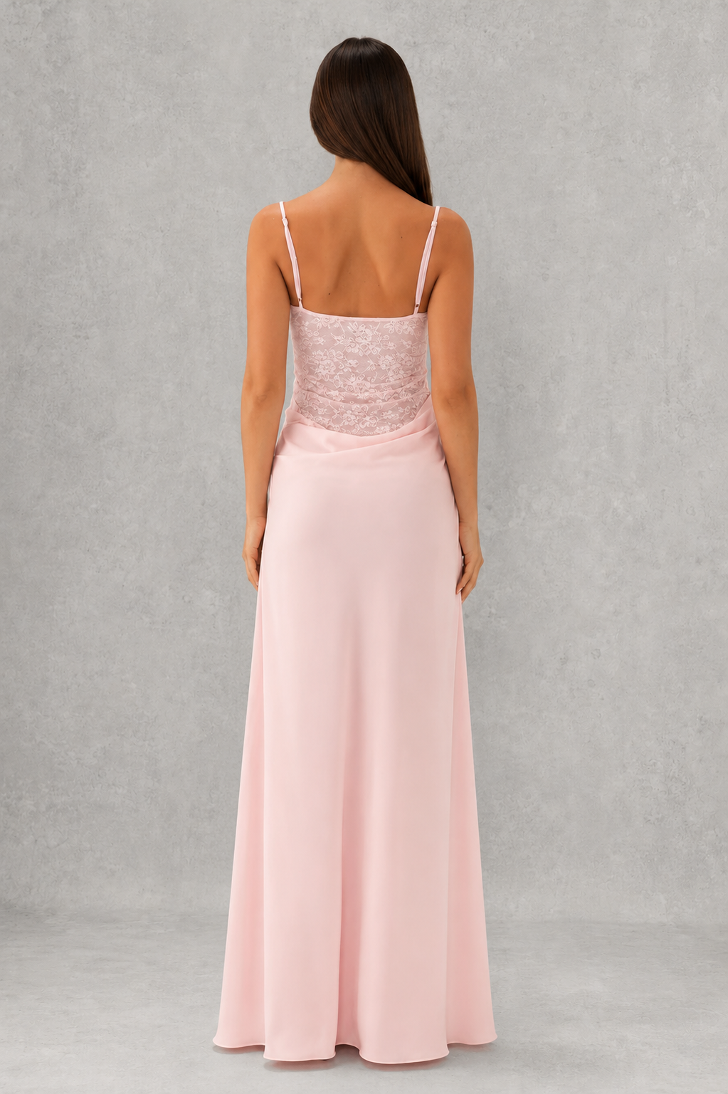 Woman wearing a pink evening gown with lace bodice on a gray background