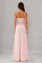 Woman wearing a pink evening gown with lace bodice on a gray background