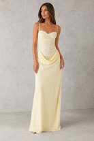 Woman wearing a long, light-colored dress against a plain background