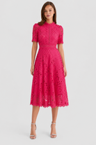 Woman wearing a pink lace dress on a white background