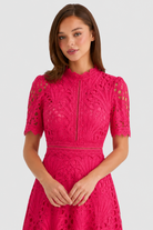 Woman wearing a pink lace dress on a light gray background