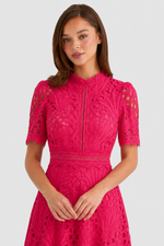 Woman wearing a pink lace dress on a light gray background