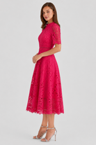 Woman wearing a pink lace dress on a light gray background