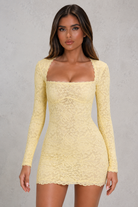 Woman wearing a yellow lace dress against a gray background