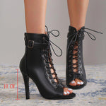 Black lace-up high-heeled shoes worn by a person on a neutral background
