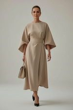 Woman in a beige dress walking on a city street.