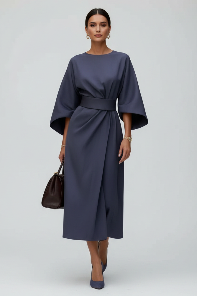 Woman in a dark blue dress walking on a city street.